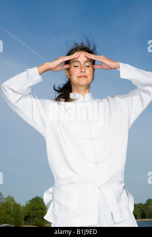 Jolie jeune femme pratiquant le Qi Gong à un lac, Qi-flux circulaire Banque D'Images