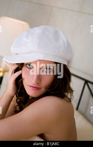 Jolie jeune femme brownhaired, avec le capuchon blanc, assis sur un lit Banque D'Images