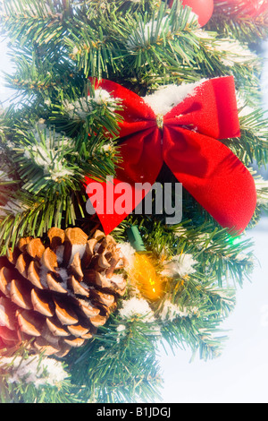 Close up of a snow covered bow & pomme de pin sur une couronne de Noël en hiver Banque D'Images