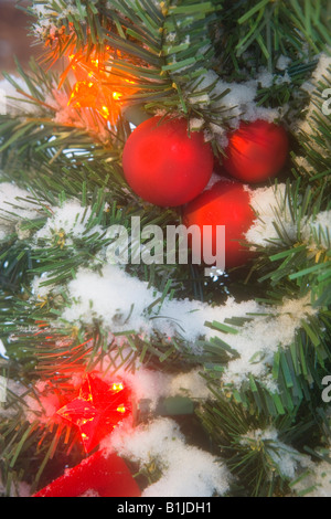 Close up of a snow covered lights & ornements sur une couronne de Noël en hiver Banque D'Images