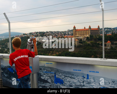 Garçon au télescope sur un point de vue, avec vue sur la ville et le château de Bratislava, Slovaquie, Bratislava Banque D'Images