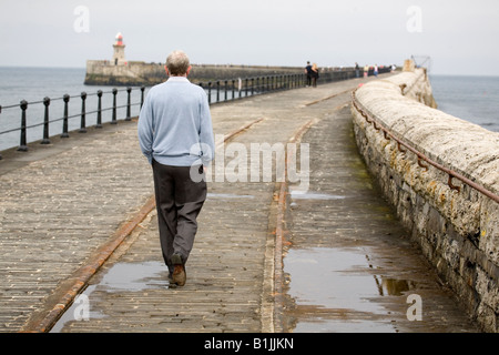 Un homme marche vers le phare sur la jetée sud de la Tyne à South Shields, en Angleterre. La jetée est un mile de long. Banque D'Images