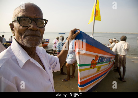 Un homme aide à terre d'un bateau de pêche sur la plage à près de Kollam Thangasseri au Kerala, en Inde. Banque D'Images