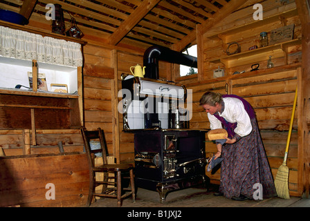 Femme de la reconstitution médiévale la cuisson du pain dans le vieux poêle Four à CottonWood House Historic Site près de Quesnel, Colombie-Britannique, Canada Banque D'Images
