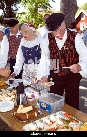 Les personnes âgées en robe folk traditionnel servant eux-mêmes à des jardins de l'île de West Sweden SWEDEN Öckerö Banque D'Images