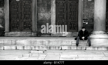 Un homme est assis seul dans la cour de l'Blue (Sultan Ahmed) mosquée à Istanbul, dans le quartier Sultanhamet rustique. Banque D'Images