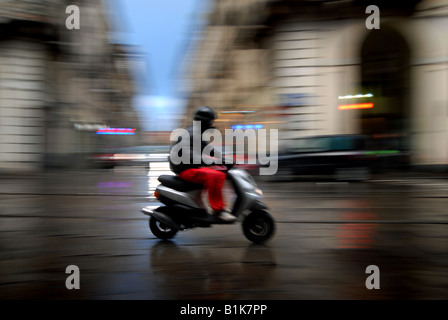 Un scooter à travers la pluie le long de la Via Po à Turin, Piémont, Italie. Banque D'Images