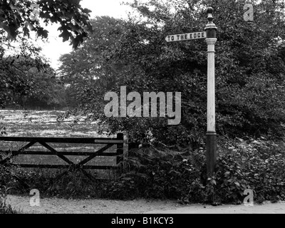 Ancien fer à repasser sign post disant À LA PÉRIPHÉRIE. À Wilmslow, Cheshire, près de Manchester. Photographie en noir et blanc. Monochrome. Banque D'Images