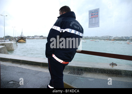 Un pompier, se pencha sur la vitre d'un abribus, est en attente pour le bateau de "Ile de Batz" Banque D'Images