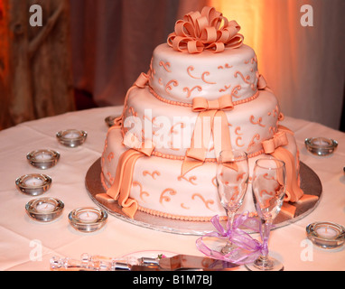 Gâteau de mariage à trois niveaux et verres de champagne sur une table