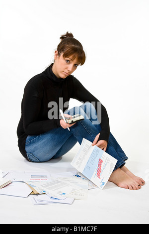 Femme, 20 ans, assise sur le sol entouré de factures. Banque D'Images