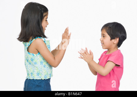 Profil de côté deux filles jouer patty cake and smiling Banque D'Images