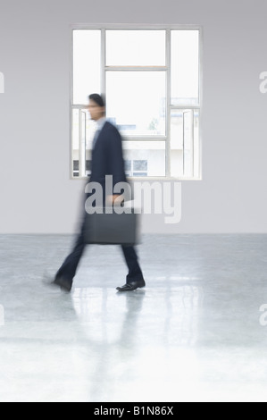 Portrait of a businessman carrying a briefcase in an office Banque D'Images