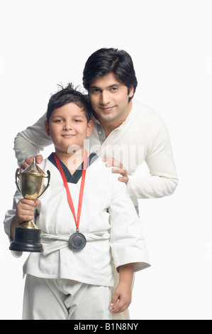 Portrait of a Boy holding a trophy avec son père derrière lui Banque D'Images