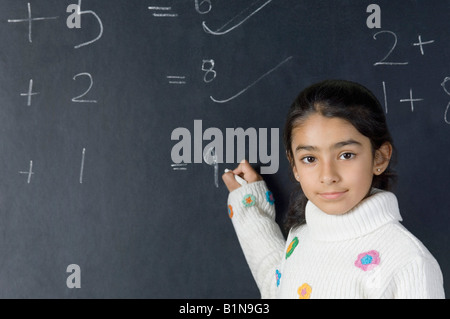 Portrait d'une fille la résolution des symboles mathématiques sur un tableau noir Banque D'Images