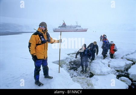 Les touristes d'être guidé sur la glace pendant une tempête de neige sur l'Antarctique pour une visite à Port Lockroy. Banque D'Images