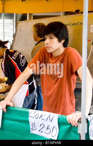 Jeune adolescente de 14 ans de vendre des épis de maïs grillés. Grand Old jour Foire de Rue St Paul Minnesota USA Banque D'Images