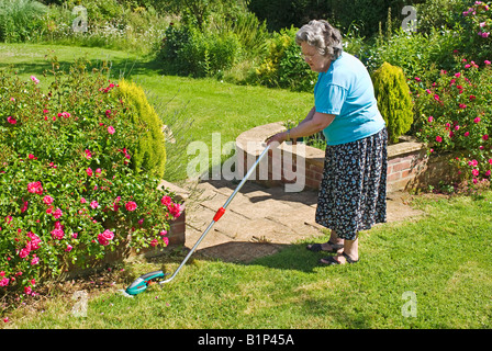 Dame à l'aide d'un jardinier sans fil Bosch Isio taille-bordures gazon en Juin Banque D'Images