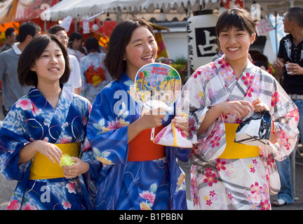 Trois jeunes filles vêtues de robes yukata en coton d'été découvrir les sites et les sons d'une fête locale Banque D'Images