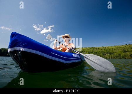Une jeune femme à bord d'un bateau gonflable sur le "Gour de Tazenat' (France). Jeune femme en canoë gonflable sur le Gour de Tazenat. Banque D'Images