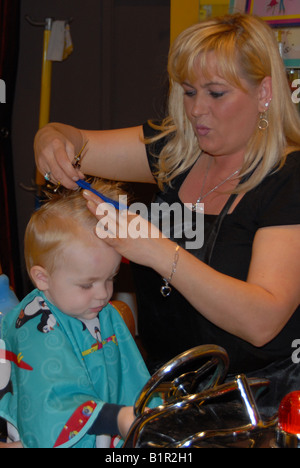 Un bambin se prépare pour sa première coupe de cheveux à un salon pour les enfants. Banque D'Images