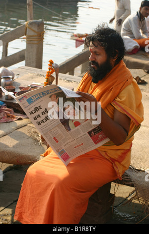 Sadhu reading newspaper in Varanasi le matin après l'assassinat de Benazir Bhutto Banque D'Images