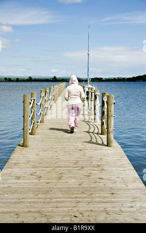 Une femme marche le long d'une jetée à Oxford Island vêtu d'un sweat Banque D'Images