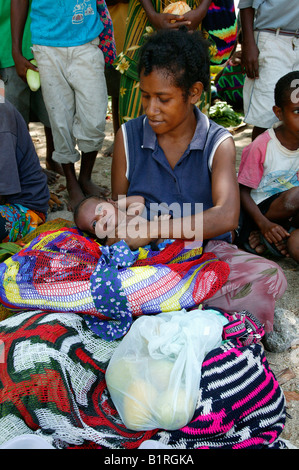 Femme avec bébé fait main vente Bilum sacs à un marché, Heldsbach, Papouasie-Nouvelle-Guinée, la Mélanésie Banque D'Images