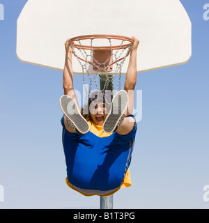 Un adolescent excité se bloque à partir d'un panier de basket-ball Banque D'Images