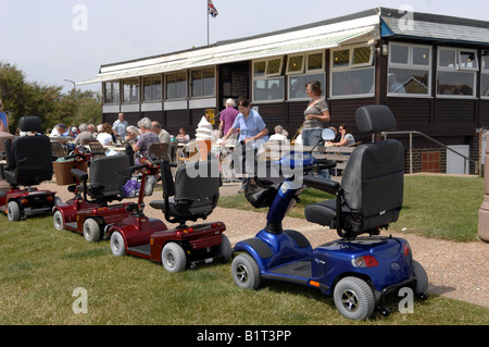 Scooters de mobilité utilisés principalement par OAP garés à l'extérieur d'un café près de Worthing Sussex UK Banque D'Images