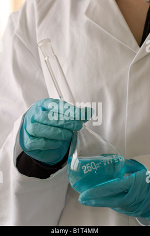 Gants en nitrile résistant aux produits chimiques utilisés pour traiter une fiole jaugée. Banque D'Images