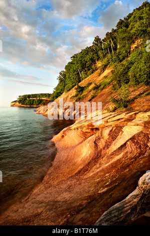 Quand le soleil se couche sur le lac Supérieur, le grès de Pictured Rocks National Lakeshore commencent à briller une orange couleur rouille. Banque D'Images