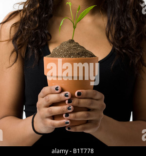 Une fille est titulaire d'une plante en pot Banque D'Images