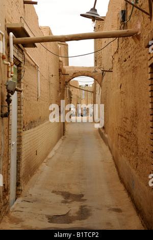 Ruelle longue dans l'ancien secteur de Yazd où deux jeunes parler à l'autre, l'un à cheval sur une moto. Banque D'Images