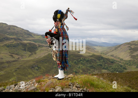 Solitaire écossais Piper jouant à la cornemuse et portant tartan à carreaux kilt, sporran et barbu sur les sommets de colline d'Invernesshire, Ecosse royaume-uni Banque D'Images