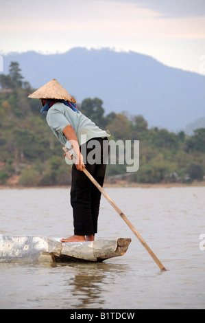 Vietnamese woman paddling un bateau sur le lac Lak dans la lumière du soir Vietnam Banque D'Images