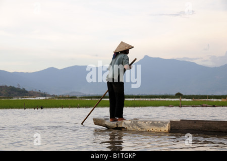 Femme Vietnaese paddling un bateau sur le lac Lak dans la lumière du soir Banque D'Images