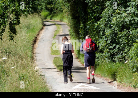 Les promeneurs sur un chemin de campagne dans les Cotswolds Gloucestershire Angleterre Banque D'Images