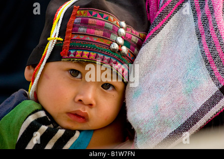 Un bébé enfant hilltribe Akha repose sur l'épaule de sa mère dans la ville frontière birmane de Tachilek. Banque D'Images