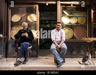 Le Caire, Egypte, Afrique du Nord. Chaudronniers assis à l'extérieur de leur magasin dans le marché Khan al Khalili Banque D'Images