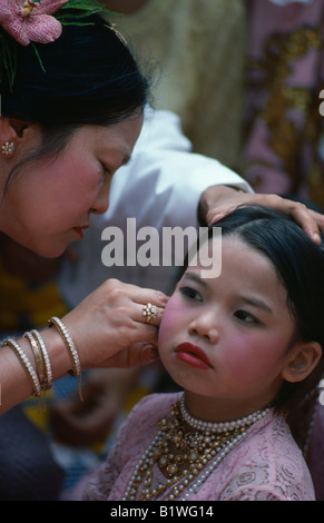 Asie du Sud-Est Birmanie Myanmar Enfants jeune fille portant le maquillage et les bijoux ayant son oreille percée par femme plus âgée. Banque D'Images