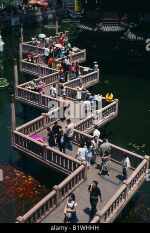 Asie Chine Shanghai Yu Gardens sur zig-zag passerelle avec les gens sur l'étang avec une masse d'argent et orange carpe koï poisson. Banque D'Images