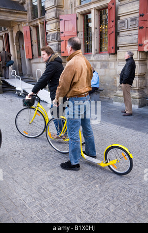 Deux hommes sur Kickbikes sur le côté de l'Hôtel de Ville, Grand-Place, à Delft. Aux Pays-Bas. Banque D'Images