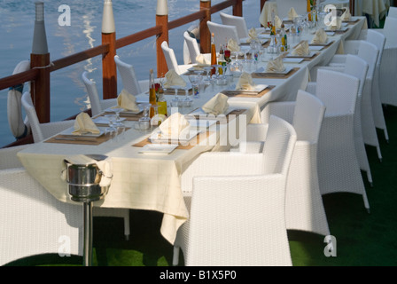 Vue horizontale d'une longue table vide pour une grande partie à l'extérieur prêt pour le dîner dans un restaurant au bord de l'eau cher Banque D'Images