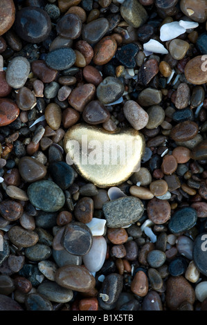 Galets en forme de coeur d'or entre les galets sur une plage. Plage de Findhorn, Moray, Ecosse Banque D'Images