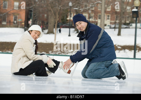 Portrait d'un jeune homme attachant lacets de patins d'une jeune femme Banque D'Images