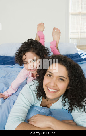 Portrait of a Mid adult woman with her daughter lying on the bed Banque D'Images