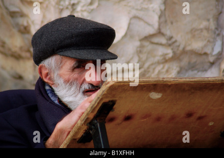 Un homme âgé est assis dans la prière devant le mur occidental de Jérusalem, lieu saint du judaïsme. Banque D'Images