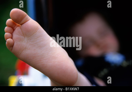 Le pied de la petite fille est rapproché alors qu'elle est dans sa poussette pieds nus Banque D'Images