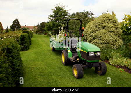 JOHN DEERE 4010 TRACTEUR ET REMORQUE TRAVAILLANT DANS UN JARDIN. Banque D'Images